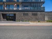 a black brick building with stairs on one side and a glass balcony on the other