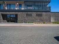 a black brick building with stairs on one side and a glass balcony on the other