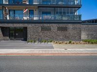 a black brick building with stairs on one side and a glass balcony on the other