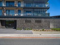 a black brick building with stairs on one side and a glass balcony on the other