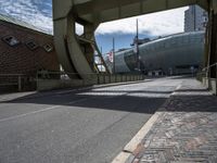 the empty street is lined with brick streets and buildings near by, as the sun shines in