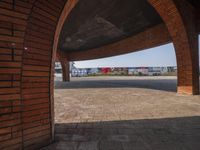 a brick archway on the sidewalk of a train station with trains parked underneath it in a blurry shot