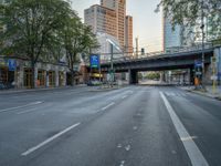 a city street that has a bridge over the road at sunset on a clear day