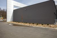 a building with a gray and white striped exterior and windows in front of gravel and rocks in front