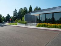 a building is surrounded by flower beds and trees and grass on the sidewalk in front of it