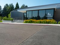 a building is surrounded by flower beds and trees and grass on the sidewalk in front of it