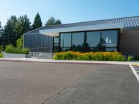 a building is surrounded by flower beds and trees and grass on the sidewalk in front of it