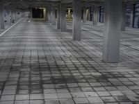 a building that is empty and grey with light coming through the ceiling and stone pavers on the ground