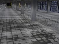 a building that is empty and grey with light coming through the ceiling and stone pavers on the ground