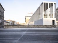 the large, empty sidewalk with multiple columns in front of the building with two signs