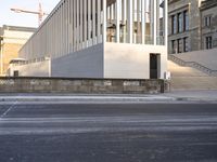 the large, empty sidewalk with multiple columns in front of the building with two signs