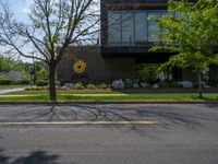 a building with a logo painted on the side near a street that has a sidewalk next to it