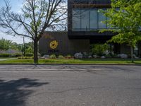 a building with a logo painted on the side near a street that has a sidewalk next to it