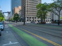 the green paint is painted on a bike path in front of an office building and large, trees