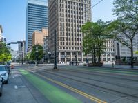 the green paint is painted on a bike path in front of an office building and large, trees