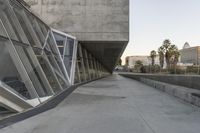 a sidewalk near the large building with several windows and people walking around outside of it