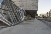 a sidewalk near the large building with several windows and people walking around outside of it