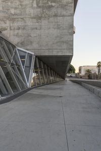 a sidewalk near the large building with several windows and people walking around outside of it