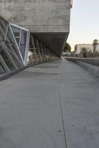 a sidewalk near the large building with several windows and people walking around outside of it