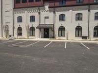 an empty parking lot in front of a large building with two brick buildings on the side