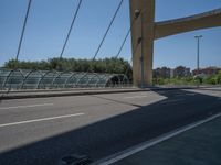 a truck driving across a bridge near a street corner near buildings and a bridge with many cables