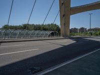 a truck driving across a bridge near a street corner near buildings and a bridge with many cables