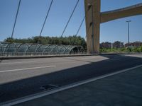 a truck driving across a bridge near a street corner near buildings and a bridge with many cables