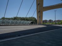 a truck driving across a bridge near a street corner near buildings and a bridge with many cables