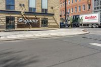 two trucks parked in front of a grocery store on the side of a street in the middle of town