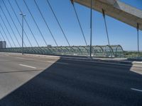 a truck driving across a bridge near a street corner near buildings and a bridge with many cables