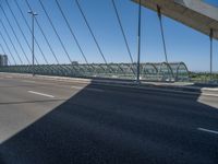 a truck driving across a bridge near a street corner near buildings and a bridge with many cables