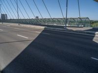 a truck driving across a bridge near a street corner near buildings and a bridge with many cables