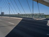 a truck driving across a bridge near a street corner near buildings and a bridge with many cables