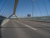 a truck driving across a bridge near a street corner near buildings and a bridge with many cables