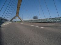 a truck driving across a bridge near a street corner near buildings and a bridge with many cables