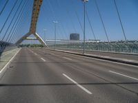 a truck driving across a bridge near a street corner near buildings and a bridge with many cables