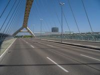 a truck driving across a bridge near a street corner near buildings and a bridge with many cables