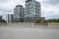 the gray building is built along the street side with high buildings in the background for urban design