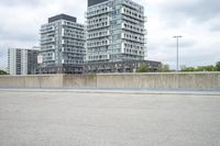 the gray building is built along the street side with high buildings in the background for urban design