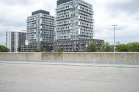 the gray building is built along the street side with high buildings in the background for urban design