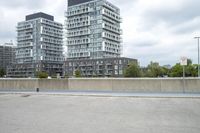 the gray building is built along the street side with high buildings in the background for urban design