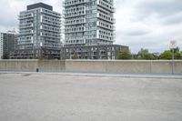the gray building is built along the street side with high buildings in the background for urban design