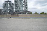 the gray building is built along the street side with high buildings in the background for urban design