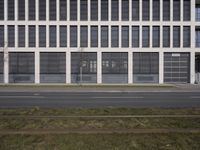 this is an empty sidewalk in front of a building with closed doors and blinds on it