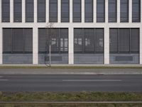 this is an empty sidewalk in front of a building with closed doors and blinds on it