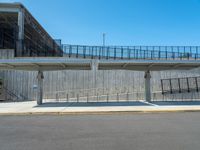 two people crossing over a bridge in a parking lot with a sidewalk below them and stairs