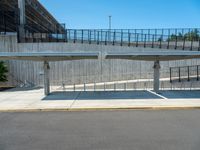 two people crossing over a bridge in a parking lot with a sidewalk below them and stairs