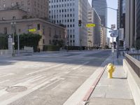 an empty city street in the daytime with a building on both sides of it and a yellow fire hydrant on the other side