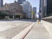 an empty city street in the daytime with a building on both sides of it and a yellow fire hydrant on the other side