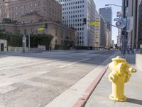 an empty city street in the daytime with a building on both sides of it and a yellow fire hydrant on the other side